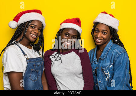 Ritratto di donna africana in cappelli di Babbo Natale isolato su sfondo giallo Foto Stock