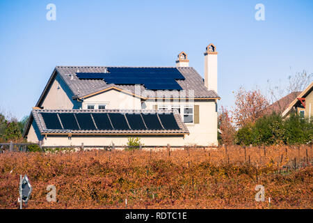 Pannelli solari sul tetto degli edifici residenziali; vigneti in primo piano; Livermore, est la baia di San Francisco, California Foto Stock