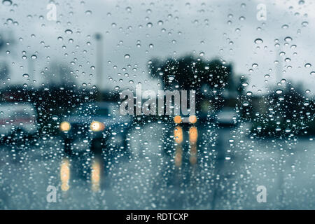 Cars driving attraverso heavy rain; le gocce di pioggia sul parabrezza Foto Stock