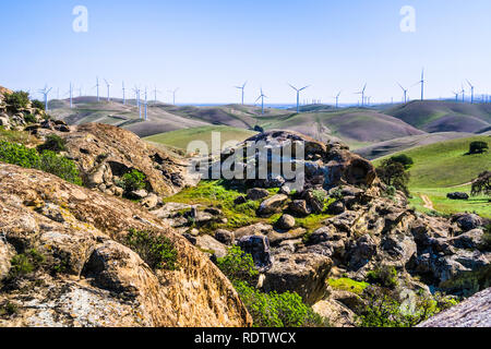 Le formazioni rocciose sulle colline della costa della contea di Contra; le turbine eoliche in background, east bay area di San Francisco, California Foto Stock