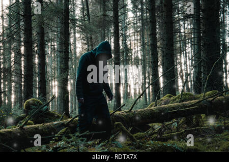 Un losco lone incappucciati figura con la luce proveniente dal suo volto, in una foresta in inverno circondato da fantasmi di sfere di luce con un oscuro disattivato modifica. Foto Stock
