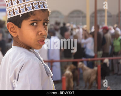 Nizwa, Oman - 2 Novembre 2018: Ritratto di bambino girando attorno sorpreso dalla telecamera al venerdì sul mercato degli animali in Nizwa Foto Stock