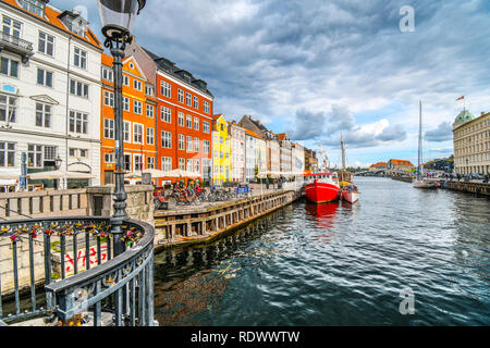 I turisti passeggiata, fare acquisti e cenare presso caffetterie lungo la strada in una giornata autunnale del xvii secolo waterfront canal Nyhavn a Copenaghen, in Danimarca. Foto Stock