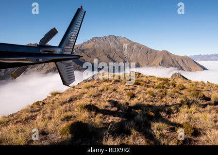 A metà mattina scena su una cima nei pressi del Monte Creighton al di sopra del cloud-coperta Lago Wakatipu vicino a Queenstown sull'Isola del Sud della Nuova Zelanda. Foto Stock