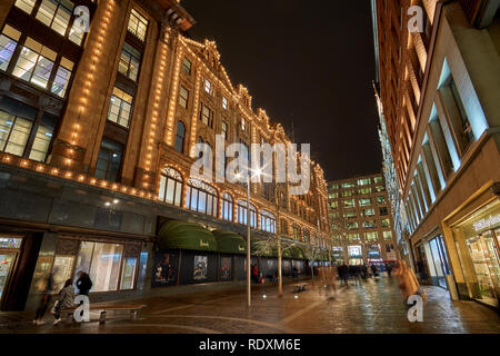 Vista esterna dei magazzini Harrods a Londra di notte durante il periodo invernale. Il traffico notturno street scenario in una tipica giornata di pioggia nel Regno Unito Foto Stock