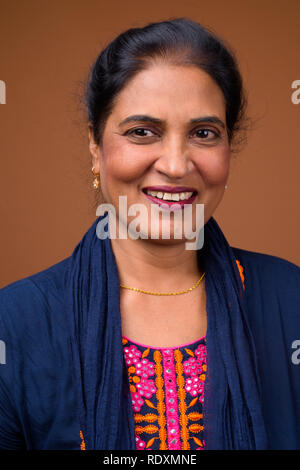 Faccia della bella donna indiana sorridente contro sfondo marrone Foto Stock