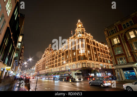 Vista esterna dei magazzini Harrods a Londra di notte durante il periodo invernale. Il traffico notturno street scenario in una tipica giornata di pioggia nel Regno Unito Foto Stock