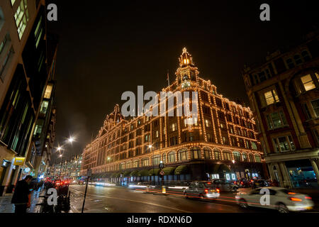 Vista esterna dei magazzini Harrods a Londra di notte durante il periodo invernale. Il traffico notturno street scenario in una tipica giornata di pioggia nel Regno Unito Foto Stock