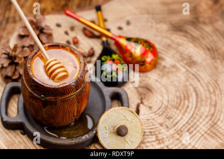 Il miele stick in una canna con miele fresco e dipinto russo cucchiai di legno. Il rustico. Close-up. Foto Stock