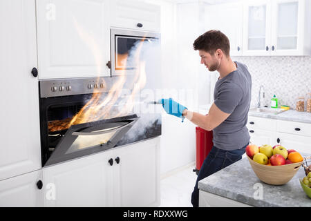 Uomo che usa estintore per mettere fuori fuoco dal forno a casa