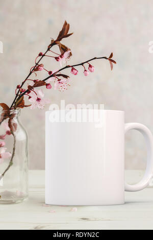 Schermata bianca vuota mug accanto a germogliare in un vaso di vetro. Perfetto per le imprese che vendono tazze, appena sovrapporre il tuo preventivo o sulla progettazione per l'immagine. Foto Stock