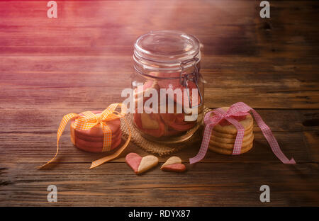 Il giorno di San Valentino i cookie in un barattolo di vetro su sfondo di legno Foto Stock