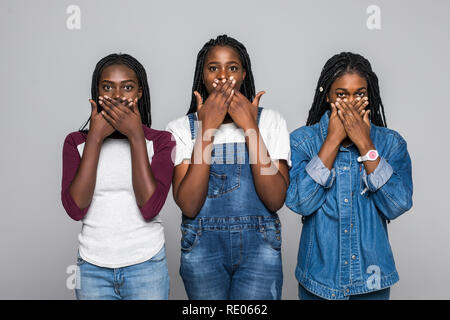 Tre giovani belle donne africane che copre la bocca con la mano su sfondo bianco. Foto Stock