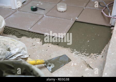 Una costruzione di plastica con benna a base cementizia collante pronto per essere utilizzato per l'incollaggio di piastrelle in ceramica. Foto Stock