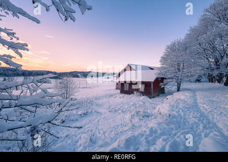 Casa abbandonata con paesaggio innevato e tramonto in serata invernale in Finlandia Foto Stock