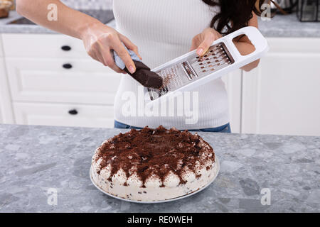 Ritratto di un sorridente giovane donna cioccolato reticolo sulla torta Foto Stock