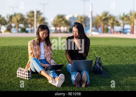 Due ragazze asiatiche lavorando su laptop all'aperto Foto Stock