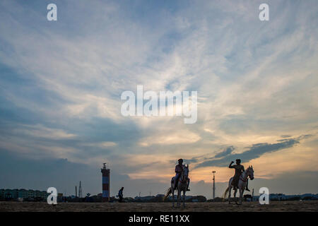 Equitazione al tramonto sulla spiaggia di Marina di Chennai, India meridionale come il sole scende Foto Stock