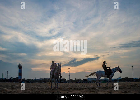 Equitazione al tramonto sulla spiaggia di Marina di Chennai, India meridionale come il sole scende Foto Stock