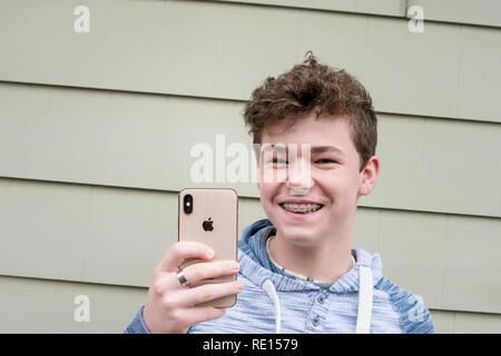 Ritratto di un adolescente che sorregge il nuovo iPhone X e sorridente Foto Stock