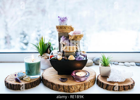 Spirituale rilassante Feng Shui altare con la natura, di acqua e di elemento fuoco. Il piano portapaziente piccola fontana elettrica con acqua versando tazze. Simbolo di ricchezza. Foto Stock