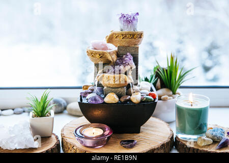 Spirituale rilassante Feng Shui altare con la natura, di acqua e di elemento fuoco. Il piano portapaziente piccola fontana elettrica con acqua versando tazze. Simbolo di ricchezza. Foto Stock