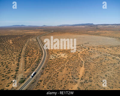 Vista aerea di un'autostrada dritta che attraversa un paesaggio desertico asciutto e sparso con un solo veicolo Foto Stock