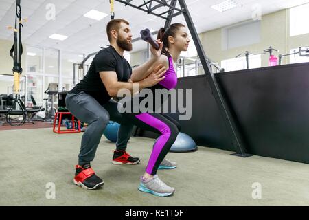 Personal fitness trainer coaching e aiutando client donna fare esercizio in palestra. Sport, il lavoro di squadra, la formazione di persone concetto. Foto Stock