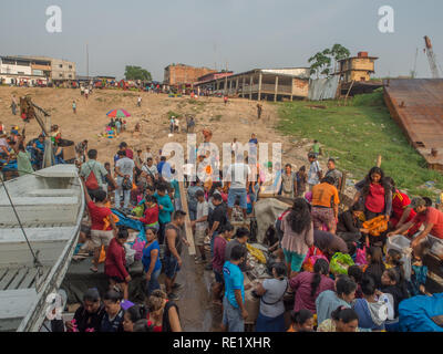 Iquitos, Perù - Sep 21, 2017: una folla di persone locali su un bordo nave da carico e una costa fangoso di una porta attraverso il fiume del Amazon in Iguitos. Foto Stock