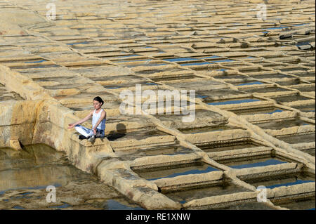 Donna meditando, seduto tra calcare le saline di Malta Foto Stock