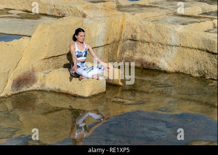 Donna meditando, praticare il "semplice" pongono fra il calcare saline di Malta Foto Stock