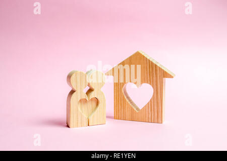 Una casa con un cuore si erge tra una coppia di amanti. Il concetto di trovare un nido d'amore. Ipoteca, acquistare credito. Il giorno di San Valentino. Housi conveniente Foto Stock