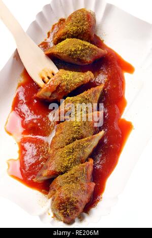 Currywurst con salsa al curry su un piatto di carta, hot salsicce di maiale Foto Stock