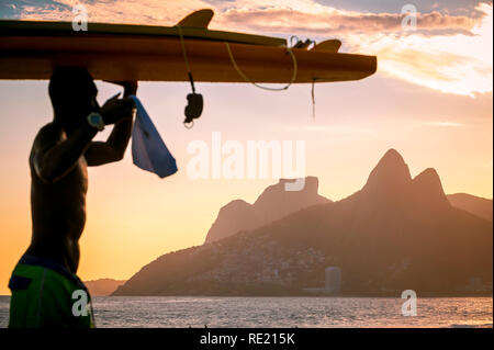 Scenic vista al tramonto dei due fratelli di montagna con il passare defocalizzata silhouette di un surfista a Rio de Janeiro in Brasile Foto Stock