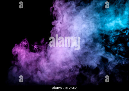 Nuvole di isolato di fumo di colore: blu, rosso, verde, rosa; scorrimento su uno sfondo nero nel buio vicino. Foto Stock