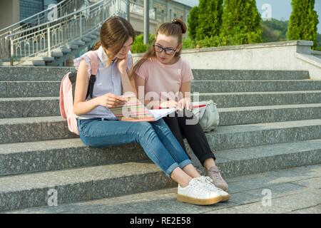 Ritratto di due studentesse di adolescenti con la scuola zaini e libri. Parlando di apprendimento. Foto Stock