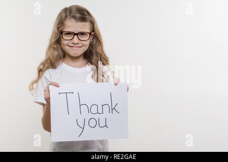 Bambine holding pezzo di carta con una parola GRAZIE. White bakgrounde, spazio di copia Foto Stock