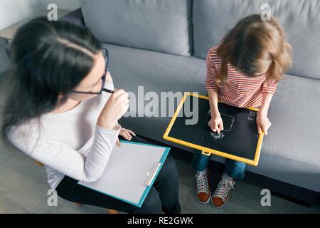 Giovani femmine psicologo parlando con il paziente bambino ragazza in ufficio. La salute mentale dei bambini. Foto Stock