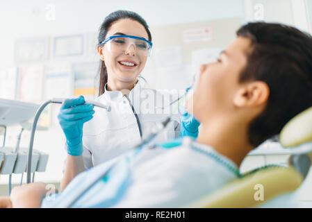 Guarnizione di tenuta del processo di installazione, odontoiatria pediatrica, bambini stomatologia. Dentista femmina denti di perforazione, clinica dentale Foto Stock