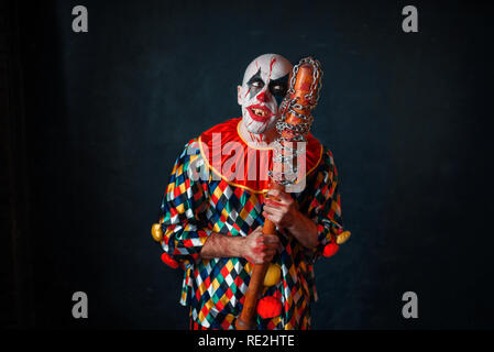 Mad sanguinosa clown con la mazza da baseball. L'uomo con il trucco in costume di halloween, zombie Foto Stock