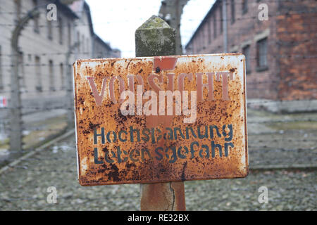 Oswiecim, Polonia. 27 gennaio, 2018. Un cartello con la scritta "ATTENZIONE: Alta tensione pericolo di vita' è attaccato ad un posto nella parte anteriore di un recinto di filo nel campo di concentramento di Auschwitz. Il 27 gennaio 1945, il campo di concentramento nazista Auschwitz-Birkenau fu liberata dal sovietico Esercito Rosso. Ogni anno in occasione dell'anniversario della liberazione superstiti provengono per commemorare i morti e a non lasciare che le atrocità cada nell'oblio. Credito: Daniel Schäfer/dpa-Zentralbild/dpa/Alamy Live News Foto Stock