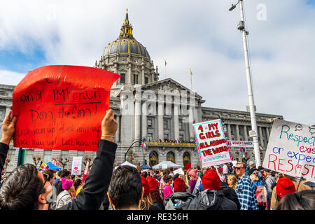 San Francisco, Stati Uniti d'America. 19 gen 2019. I partecipanti per le donne del marzo evento segni di attesa con vari messaggi; il municipio edificio visibile in background Foto Stock