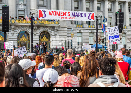San Francisco, Stati Uniti d'America. 19 gen 2019. I partecipanti per le donne del marzo evento segni di attesa con vari messaggi; la tappa di rally e il municipio edificio visibile in background Foto Stock