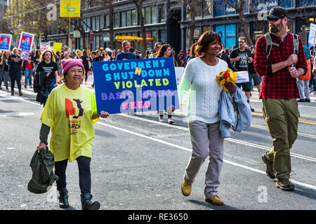 San Francisco, Stati Uniti d'America. 19 gen 2019. I partecipanti per le donne del marzo caso tenere premuto segno 'Arresto del governo violato il bisogno umano e di base' durante la marcia su strada del mercato nel centro cittadino di San Francisco Foto Stock