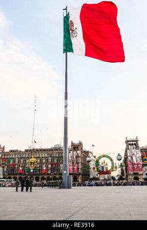 La polizia militare cadre tenendo giù il Messico bandiera nazionale al Zocalo, Città del Messico, con la gente a guardare Foto Stock