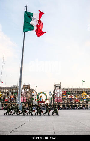 La polizia militare cadre tenendo giù il Messico bandiera nazionale al Zocalo, Città del Messico, con la gente a guardare Foto Stock