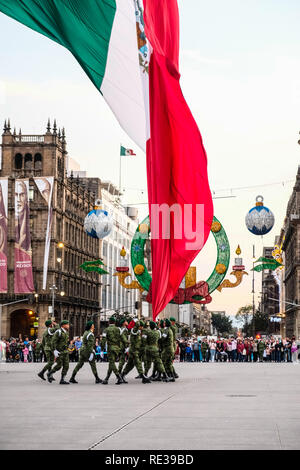 La polizia militare cadre tenendo giù il Messico bandiera nazionale al Zocalo, Città del Messico, con la gente a guardare Foto Stock