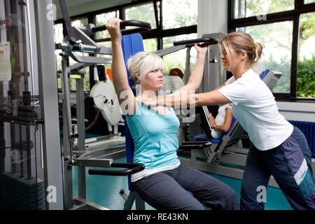 I pazienti durante la forza muscolare training su varie macchine in aula, fisioterapia in malattie neurologiche Foto Stock