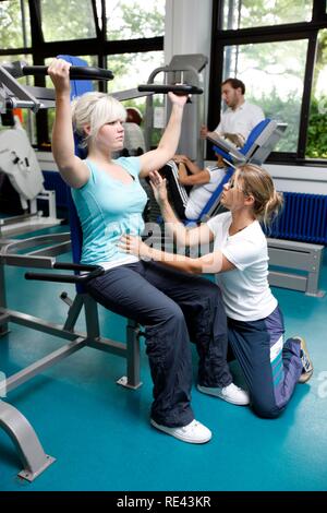 I pazienti durante la forza muscolare training su varie macchine in aula, fisioterapia in malattie neurologiche Foto Stock