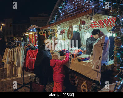 Brasov, Romania - 2 Dicembre 2018: la madre e il bambino acquista tradizionale Rumena vestiti fatti in casa sul display in corrispondenza di uno degli stand presso la strada di Natale Foto Stock